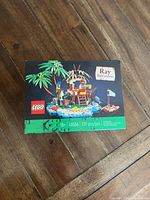 Front of the new, unopened LEGO Ray the Castaway set box showing the assembled set on an island with palm trees.