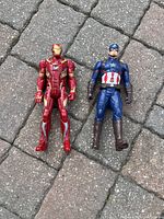 Front view of Iron Man and Captain America Marvel action figures on paved surface.