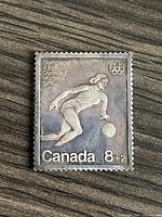 Front of Montreal 1976 Olympic silver stamp showing basketball player and text.