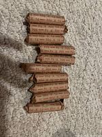 10 rolls of Canadian pennies wrapped in brown paper, marked with '50¢ X 1¢' indicating 50 pennies per roll.