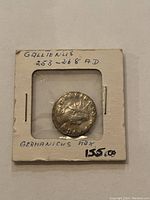 Obverse side of Roman silver coin showing two facing helmeted busts and inscriptions on holder labeled 'Gallienus 253-268 AD Germanius Max'