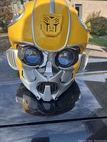Front view of Bumblebee helmet showing detailed yellow and silver design with Autobot insignia on forehead.