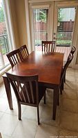 Full view of rectangular wood dining table with six chairs around it, showing overall condition and setting.