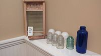 Lot arranged on corner shelf showing insulators, clothespins, blue bottle and washboard surface