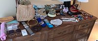 Photo showing a wide view of the dresser top with all items spread out, including bags, jewelry, belts, sunglasses, music boxes, and figurines