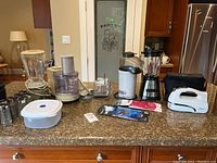 Full kitchen counter view with all appliances and items displayed including Philips blender, Braun food processor, air popcorn popper, Hamilton Beach blender, Oster hand beater with accessories, spice shakers, cookie jar, and additional kitchenware.