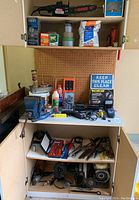 Wide view of multiple shelves showing diverse tools including vise, drill bits, wrenches, oil cans, work light and boxes.