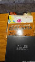 Photo showing four vinyl record albums stacked: Stevie Wonder, Diana Ross join The Temptations & The Supremes, Son House / J.D. Short Delta Blues, Eagles The Long Run.