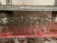 Front view of multiple clear glass Mason jars arranged on a shelf with various embossed designs, showing quantity and condition.