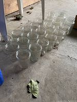 Photo of 22 clear glass mason jars arranged on concrete floor, showing their uniform size and shape.