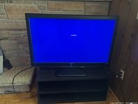 RCA flat screen TV on top of dark wooden TV stand, showing TV screen with 'No Signal' message on blue screen