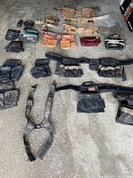 Overview of assorted tool belts, pouches, and holders arranged on floor showing various materials, colors, and styles.