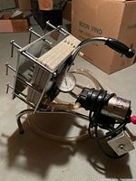 Buon Vino wine pump and filter showing metal frame, stacked filter plates, pressure gauge, and attached tubing. Original box in background.