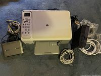 Photo showing HP Photosmart C4180 printer with power and USB cables included alongside Arris modem and other cables.