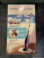 Front view of boxed Bionaire 1500W Dual Function Steam Mop showing product features and image.