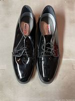 Top down images of the pair of black patent leather Capps Air-lite dress shoes size 11 with lace-up closure showing condition and branding inside