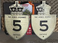 Two vintage Ontario metal highway signs for The King's Highway 5 with crown emblems, shown side by side against a black background.