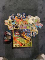 Full view of Pokémon Battle Academy board game box, three decks of cards spread out, and metal tin opened with cards.