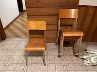Nine stackable chairs in a room, one separated and eight stacked.