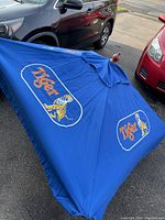 View of blue outdoor patio umbrella laid flat showing Tiger Beer logos and tiger graphic on fabric.