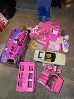 Full view displaying pink Barbie Starlight Motorhome vehicle parts laid out with box and accessories, a white Barbie Ferrari convertible, and mixed Barbie dolls and parts on floor.