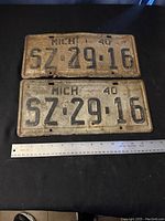 Two Michigan license plates from 1940 measuring about 14 x 6.5 inches showing rust and wear with black embossed numbers 'SZ 29 16' on cream background.