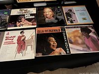 Top view of six LP records on a black surface, showing album covers: Julie London, Betty Carter, Sarah Vaughan, Ella Fitzgerald, Nancy Wilson, and Dinah Washington.