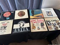 Photo of 8 LP records on black fabric background including Beyond the Fringe, Caleb, Don Johnson, Nijinsky, Evita, Juno, Big Chill albums