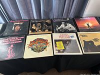 Photo showing 8 movie and stage soundtrack LP vinyl albums arranged on a black cloth-covered surface, featuring titles such as Alexis Restaurant and Go-Gos, Good Morning Vietnam, Mask, and Last Tango in Paris.