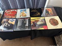 Display of eight LP soundtracks including titles like Jazz Singer, Oklahoma, Caligula, Running Scared and others.