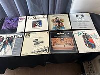 Eight LP records arranged on a surface showing varied soundtrack albums including Les Misérables, Evita, and Beverly Hills Cop.
