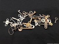 Lot of vintage keys including skeleton, Victrola, and clock winding keys spread out on a surface showcasing size and shape variations.