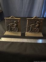 Front view of pair of metal bookends showing flute player design and size with ruler