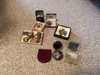 Full view of all items including trinket boxes, pocket ashtray, brooches, Birks medal, and cufflinks arranged on carpet
