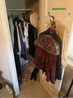Closet view showing hanging women's jackets, blouses, and some shoes on the floor