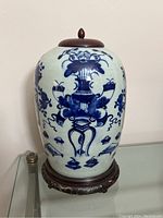 Front view of the blue and white ginger jar on the carved stand with lid in place