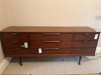 Front view showing all nine drawers, integrated handles and tapered legs