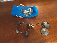 All items laid out on wood surface showing bracelet, two rings, two brooches, and pouch of fragments