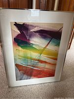 Angled full view of framed abstract print leaning against wood paneling