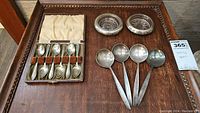 Leather-look hinged case open to show six coffee spoons held by velvet bands against a satin-lined lid