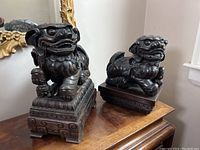 Both Foo Dog sculptures side by side on furniture surface