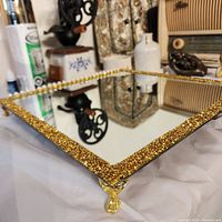Close-up image showcasing the gold beaded edge and claw feet of the square tray with mirrored bottom.
