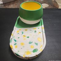 Round container placed on rectangular tray showing colors and design