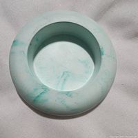 Top view of circular jesmonite candle holder showing marbled mint green and white pattern and recessed center for candle placement.