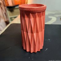 Front side view of a terracotta-colored handmade decorative vase showing geometric faceted texture.