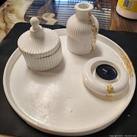 Photo showing entire set of white jesmonite tray with vase, candle holder, and lidded box with gold accents.