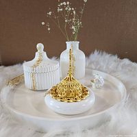 Photo of tray with all items arranged including vase with dried flowers, lidded box, incense holder, and small seashell on white fur surface