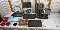 Full view of all baking pans, trays, muffin tins, ramekins, and baking accessories placed on a table.