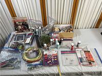Overview of entire crafting and paint collection showing paints, wires, crafting materials, plastic sheets, and guidebook.
