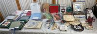 Wide view of all crafting, cross stitch fabrics, kits, patterns, puzzles, and crafting supplies spread on a table.